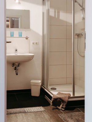 Das Badezimmer zeigt eine Dusche, ein Waschbecken und einen modernen Stil. Es ist hell und gut organisiert, ideal für die tägliche Pflege.