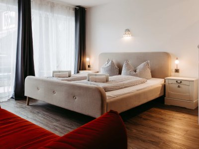 Helles Schlafzimmer mit großem Fenster, zwei Betten und gemütlicher Atmosphäre für entspannte Nächte.