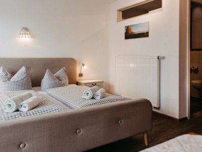 Das Schlafzimmer bietet ein warmes Ambiente mit zwei Betten, frischen Handtüchern und einem eleganten Design.