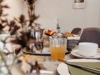 Der Tisch ist gedeckt mit Thomas, frischen Croissants und einem erfrischenden Getränk. Die Atmosphäre ist einladend und freundlich.