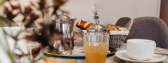 Frühstückstisch mit frischen Speisen und Getränken Der Tisch ist gedeckt mit Thomas, frischen Croissants und einem erfrischenden Getränk. Die Atmosphäre ist einladend und freundlich.