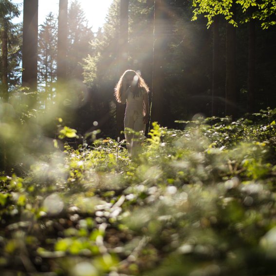 Ein Haubers Gast spaziert beim Waldbaden durch die Allgäuer Wälder nahe dem Hotel.