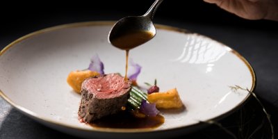Die Küche des Gourmethotels im Allgäu serviert Rinderfilet in Tannenspitzen gegart mit Rotweinjus und Kartoffelkrapfen.