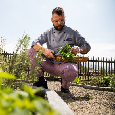 Ein Koch aus Haubers Küchenteam pflückt frische Kräuter für das Abendmenü des Gourmet-Hotels.