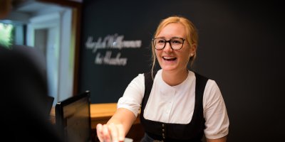 Malu informiert Haubers Gäste an der Rezeption über alles Wichtige zum Aufenthalt in Oberstaufen.