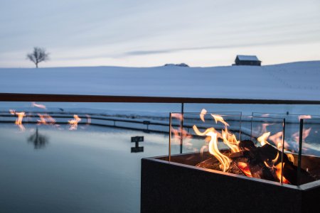 Am Abend entspannen Gäste des Skihotels am Lagerfeuer neben Haubers Natursee.