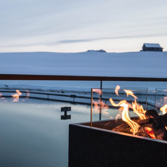 Am Abend entspannen Gäste des Skihotels am Lagerfeuer neben Haubers Natursee.