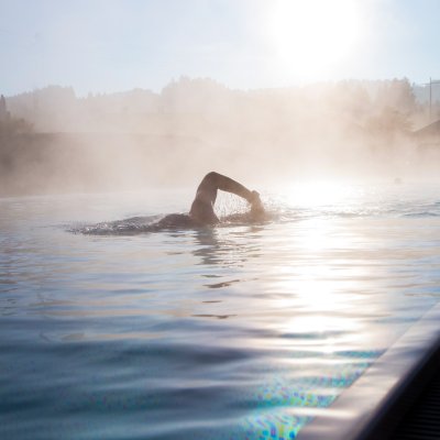 Ein Gast schwimmt bei winterlichen Temperaturen im beheizten Sportpool des Wellnesshotels im Allgäu.