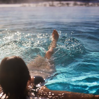 Eine Frau tritt Wasser im beheizten Hotel-Pool und genießt die Allgäuer Wintersonne.