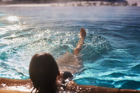 Eine Frau tritt Wasser im beheizten Hotel-Pool und genießt die Allgäuer Wintersonne.