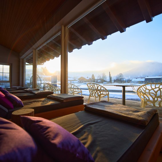 Vom Ruheraum Weitblick des Wellnesshotels Allgäu aus blicken Gäste auf den hoteleigenen Natursee.