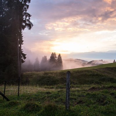 Gewitterwetter färbt den Himmel über den Allgäuer Bergen lila, bevor die Wolken die untergehende Sonne verdecken.