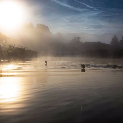 Morgens an einem sonnigen Herbsttag Schwimmer im Natursee bei Sonnenaufgang und Nebelschleier