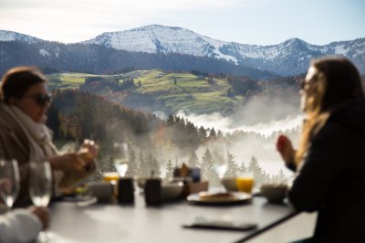 Gäste des Erwachsenenhotels frühstücken am Haubers Schwalbennest auf 950 Metern Höhe mit Ausblick auf die Allgäuer Alpen.