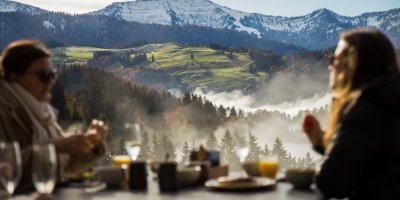 Gäste des Erwachsenenhotels frühstücken am Haubers Schwalbennest auf 950 Metern Höhe mit Ausblick auf die Allgäuer Alpen.