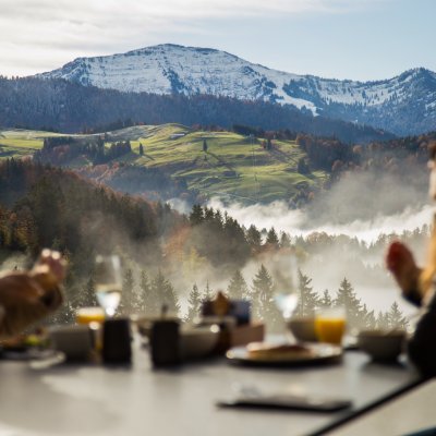 Gäste des Erwachsenenhotels frühstücken am Haubers Schwalbennest auf 950 Metern Höhe mit Ausblick auf die Allgäuer Alpen.