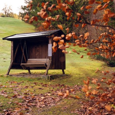 Auf dem hoteleigenen Wanderweg, dem Klimapfad, können Gäste auf der Schaukelbank rasten, die unter bunten Blättern steht.