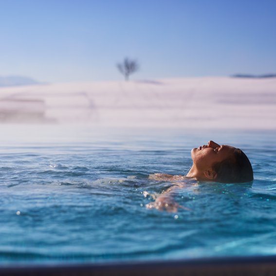 Nach einem Skitag entspannt ein Gast im warmen Relaxpool des Erwachsenenhotels.