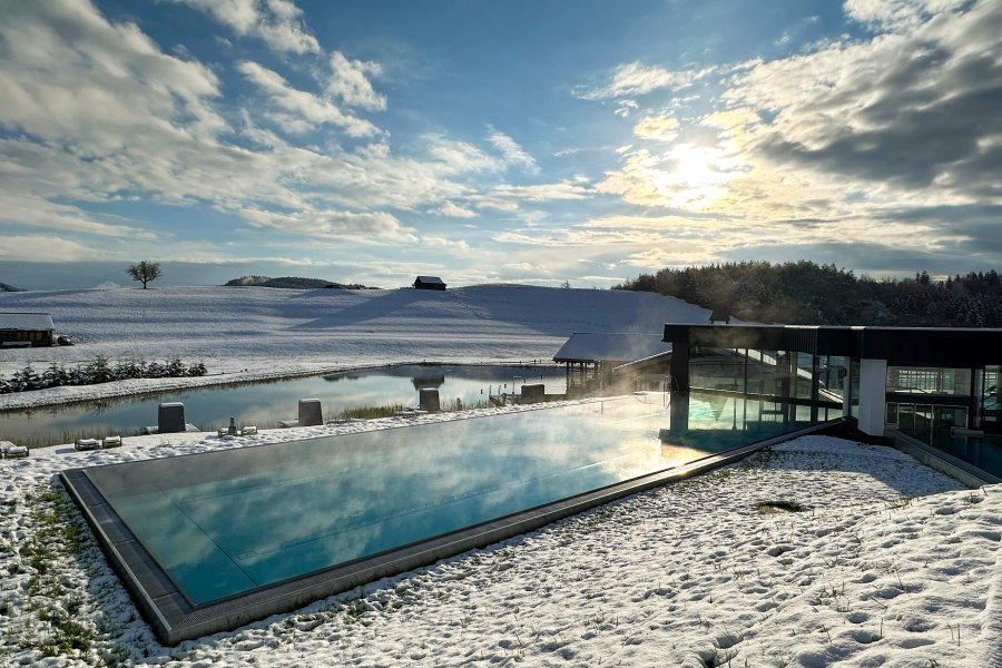 Um den Außenpool des 4-Sterne-Hotels im Allgäu, Haubers Naturresort, liegt der erste Schnee.