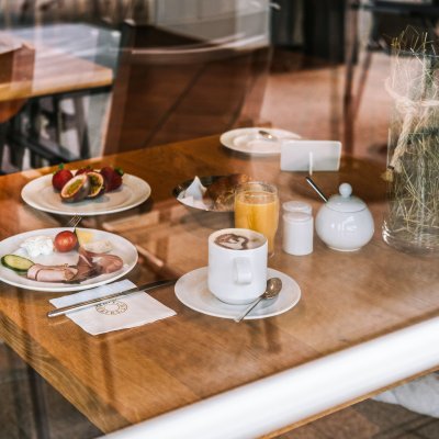 Wurst, Käse und Obst warten auf Tellern stehen auf einem Tisch im Gastraum des Haubers Naturresorts.