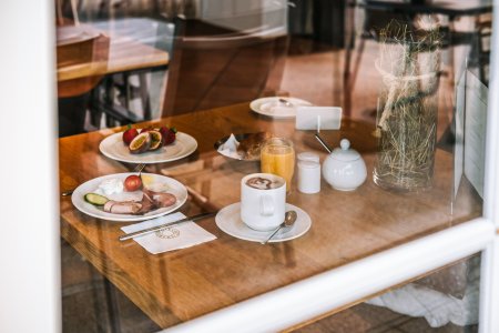 Wurst, Käse und Obst warten auf Tellern stehen auf einem Tisch im Gastraum des Haubers Naturresorts.