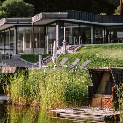 Der Wellnessbereich von Haubers Naturresort liegt direkt am Natursee mit Strandkorb und neben den Außenpools des Hotels.