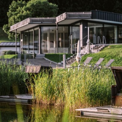 Der Wellnessbereich von Haubers Naturresort liegt direkt am Natursee mit Strandkorb und neben den Außenpools des Hotels.