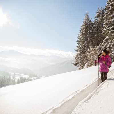 Beim Winterwandern blickt eine Frau über das 4-Sterne-Hotel nach Oberstaufen im Allgäu.