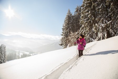 Beim Winterwandern blickt eine Frau über das 4-Sterne-Hotel nach Oberstaufen im Allgäu.