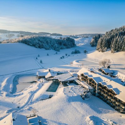 Die Wintersonne fällt auf das verschneidet 4-Sterne-Hotel, in dem Basenfasten im Allgäu möglich ist.