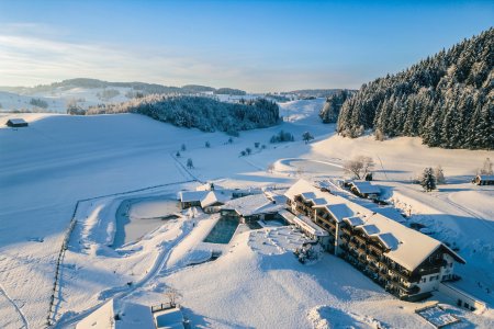 Die Wintersonne fällt auf das verschneidet 4-Sterne-Hotel, in dem Basenfasten im Allgäu möglich ist.