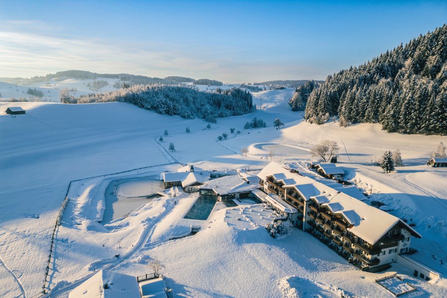 Die Wintersonne fällt auf das verschneidet 4-Sterne-Hotel, in dem Basenfasten im Allgäu möglich ist.