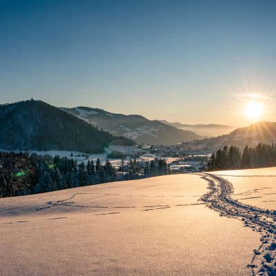 Die Wintersonne scheint über die verschneite Höhe und über Oberstaufen im Allgäu.