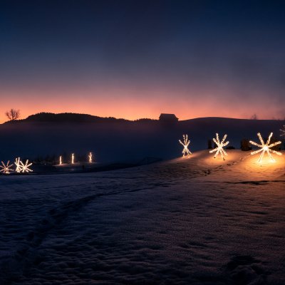 Die Leuchtsterne von Haubers Naturresort tauchen die Schneelandschaft um das Hotel in weihnachtliches Licht.