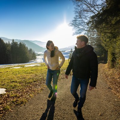 Eine Frau und ein Mann blicken sich an, während Sie vom Allgäuer Wellnesshotel zu Haubers Schwalbennest laufen.