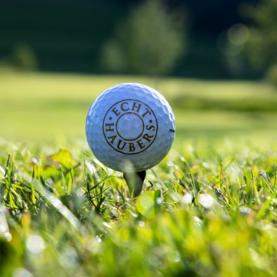 Auf dem Golfplatz mit Direkteinstieg vom Hotel aus liegt ein Golfball mit Echt Haubers Logo bereit zum Abschlag.