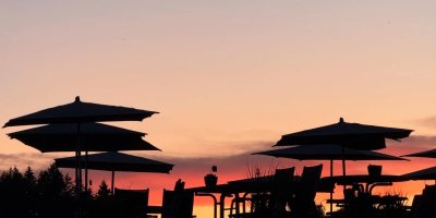 Die Silhouetten von Tischen und Sonnenschirmen bei Sonnenuntergang laden zum Entspannen in der Natur ein.