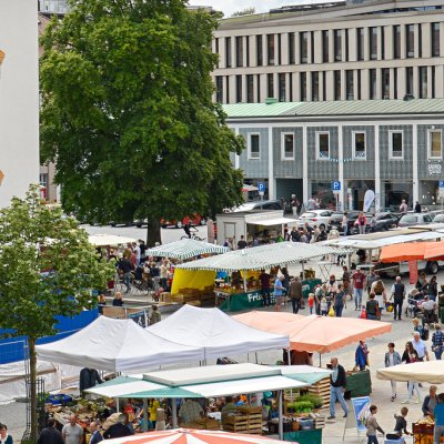 Auf dem Wochenmarkt der Stadt Kempten gehen Besucher durch die Marktstände.
