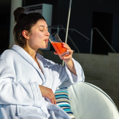 Eine Frau im Heilfastenurlaub entspannt auf einem Sofa im Haubers Naturresort und trinkt einen Heilfasten-Saft. Fasten im Haubers Naturresort ist Teil eines Gesundheitsurlaubs.