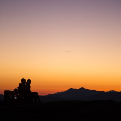 Sonnenaufgang Salmaser Höhe Paar sitzt auf einer Bank am Gipfel und genießt den Sonnenaufgang.