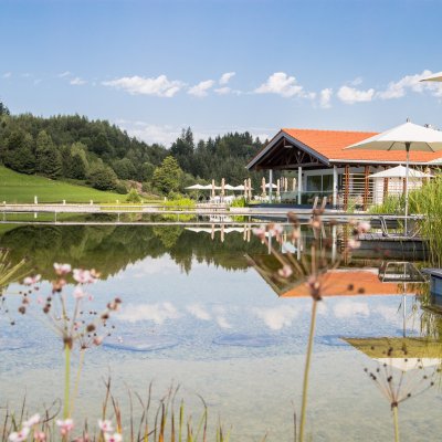 Gäste erfrischen sich nach einer Golfrunde in Haubers Natursee direkt am Wellnessbereich.