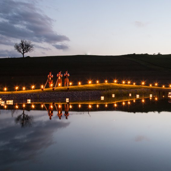 Alphornbläser spielen bei Haubers Seefest am Ufer des Natursees vor Haubers Naturresort im Allgäu.