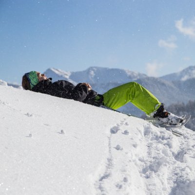 Eine Schneeschuhwanderin liegt bei einer Pause im Schnee.