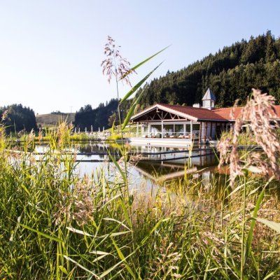 Der Haubers Natursee liegt direkt vor dem Wellnessbereich des Erwachsenenhotels, Haubers Naturresort im Allgäu.
