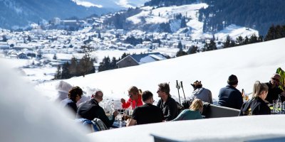 Haubers Gäste sitzen vor dem Schwalbennest in der Wintersonne und warten auf das Menü von Kulinarik im Schnee.