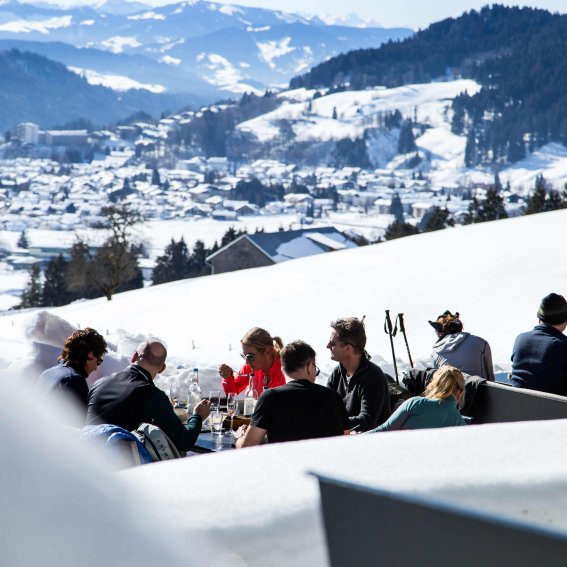 Haubers Gäste sitzen vor dem Schwalbennest in der Wintersonne und warten auf das Menü von Kulinarik im Schnee.