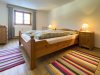 Gemütliches Zimmer mit Holzbetten und Teppichen In einem Raum stehen zwei Holzbetten mit Decken. Neben den Betten sind Nachttische und Teppiche auf dem Boden.