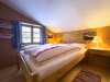 Ein Schlafzimmer in einem Holzhaus im Gebirge Ein Schlafzimmer mit einem großen Bett und einem Fenster. Das Zimmer hat Holzwände und ist hell.