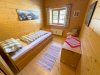 Schlafzimmer in einem Holzhaus in den Bergen Ein einfaches Zimmer mit einem Bett, Fenster und Holzdekor. Der Raum hat eine ruhige Atmosphäre und Blick auf die Berge.