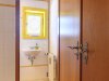 Badezimmer mit einem Fenster und einer Tür Ein Raum mit einem Waschbecken, einer Heizung und einer offenen Tür. Das Fenster hat einen gelben Rahmen.